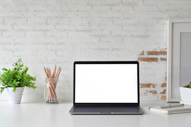 istock Workspace with blank white screen laptop on loft desk. 1064988030