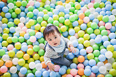 Baby playing in the pool with lots of colorful balls