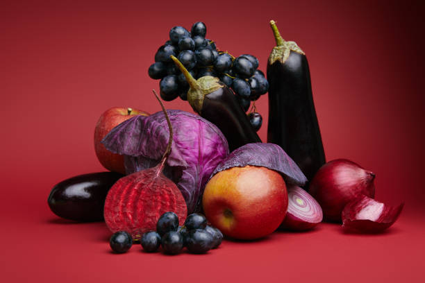 istock close-up view of fresh ripe grapes, apples, eggplants, beetroot, onions and cabbage on red 1064996852