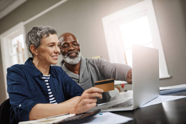 è ora di prenotare quella vacanza in pensione - home finances couple computer african ethnicity foto e immagini stock