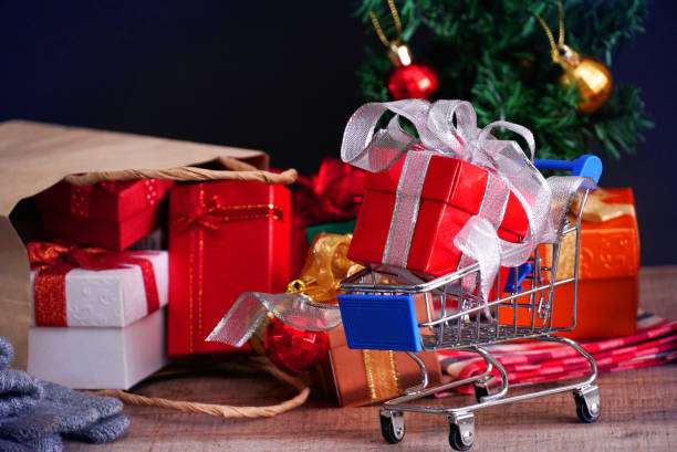 istock Red gift box on small cart with gift boxes spill out from paper bag on black background , shopping concept. 1065012964