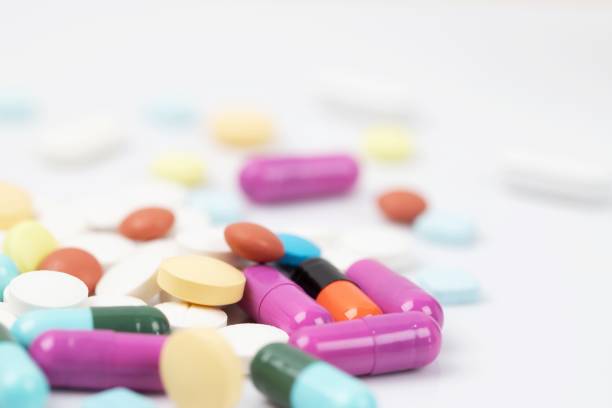 istock close up macro Pill spilling out disrupted. colorful pills capsule on to surface tablets on a table wooden background. drug medical healthcare concept. 1065016074