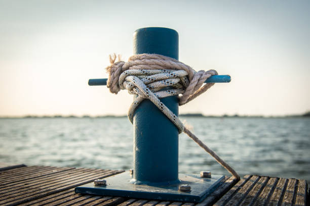 Mooring rope with a knotted end tied around a cleat on a wooden pier