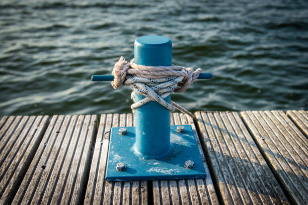 mooring bollard with a rope and a knot in front of water