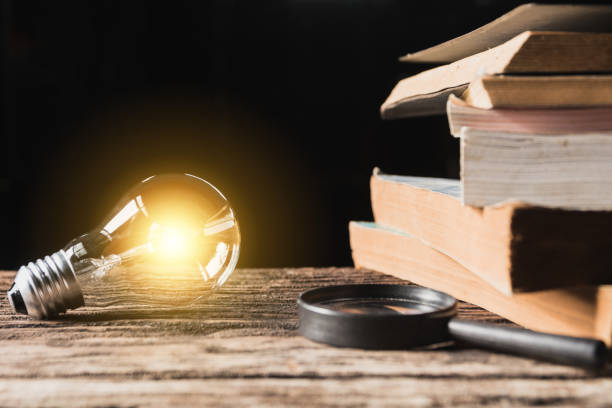 istock Light bulb and pile of book on wooden table and copy space for insert text. 1065025976