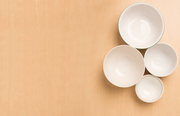 istock Four white empty bowls on light wood background, Flat Top View 1065032496
