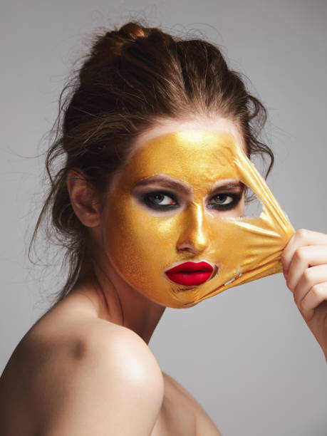 A woman with a golden face mask applied for skincare purposes, highlighting beauty routines and relaxation.