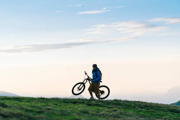 istock Man mountain bikes up grassy slope 1065043914