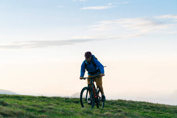 istock Man mountain bikes up grassy slope 1065043934