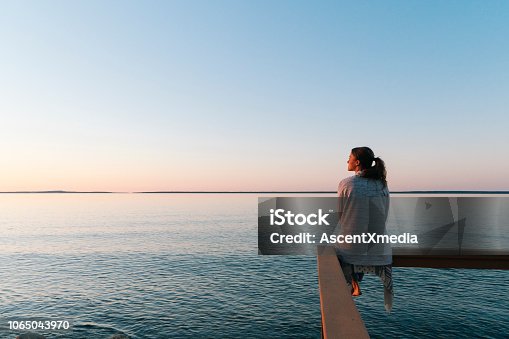 istock Young woman sitting on edge looks out at view 1065043970