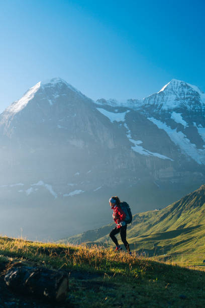 one young female hiker walks up hill - bernese oberland imagens e fotografias de stock
