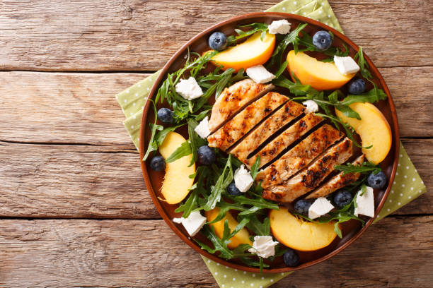 grilled chicken breast with fresh peaches, blueberries, arugula and feta cheese close-up on a plate. horizontal top view - grilled chicken fotos imagens e fotografias de stock