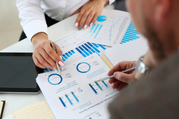 istock Female arm holding silver pen point in financial graph 1065072192