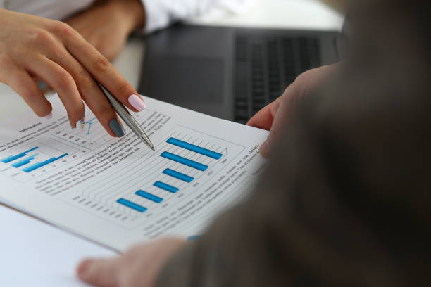 istock Female arm holding silver pen point in financial graph 1065072224