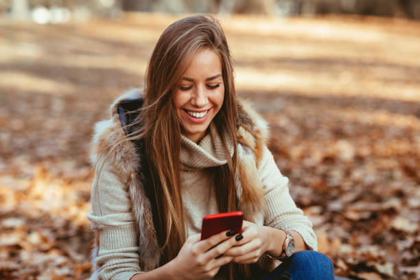 istock Young woman in the park using smartphone  and laughing 1065097184