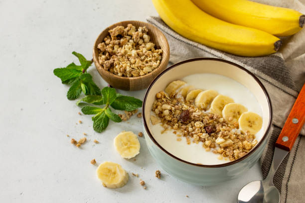 istock Granola. Granola with yogurt, chocolate and banana on a white stone table. 1065109406