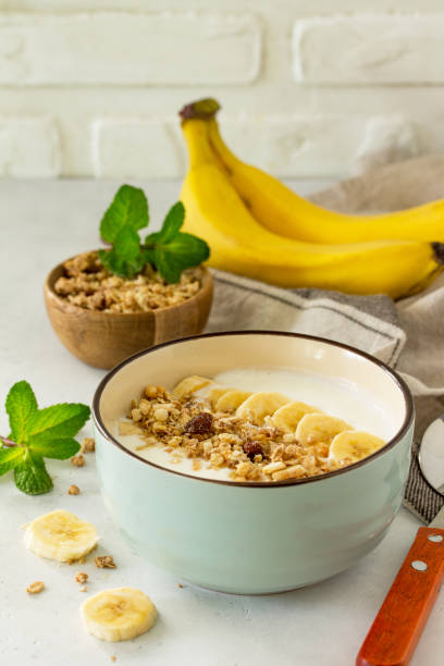 istock Granola. Granola with yogurt, chocolate and banana on a white stone table. 1065109414