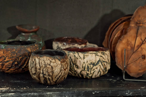 istock Clay pottery and ceramic products on a black wooden table. Home workshop. Handmade with drawings and patterns. 1065119048