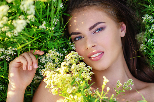 Closeup  face of young woman with clean skin. Skin care. Beautiful girl is on nature on green grass.  Portrait of a pretty  model. Caucasian woman is relaxing and enjoying with summer time. High angle.