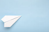 Paper plane on a blue background. Concept of flight, travel, transfer. Top view, copy space, flat lay