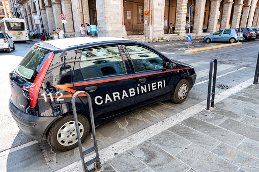 Perugia, Italy - August 29, 2018: Small Carabinieri car parked on street, road by sidewalk with old, ancient, antique architecture, building, people, tourists walking