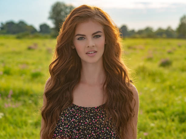 Young woman outdoors in a field. Model posing in nature on a nice summer day.