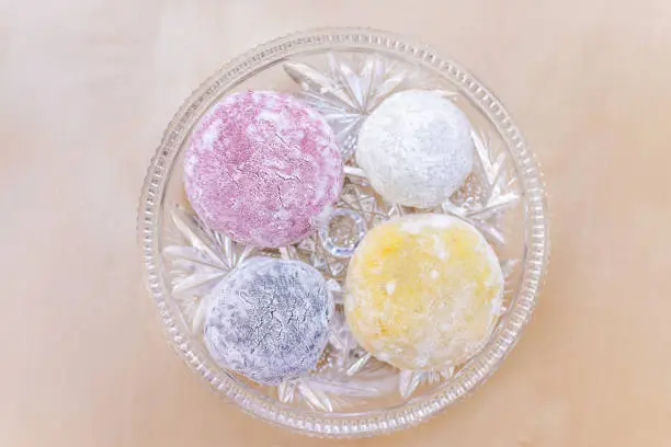 Four round whole mochi sticky glutinous rice cake dessert pieces, colorful multicolored natural food dye wagashi daifuku filled with ice cream