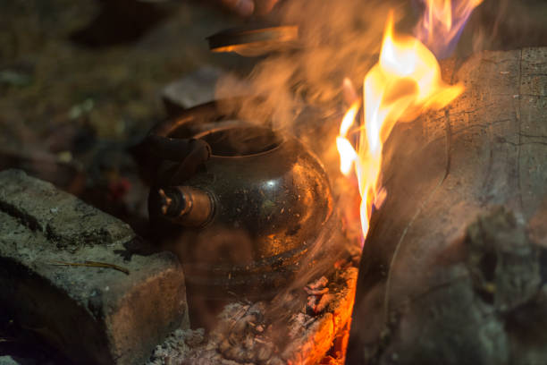 la caldera se calienta sobre un fuego por la noche al aire libre - reclusion fotografías e imágenes de stock