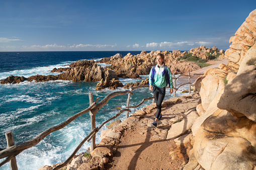 Female Tourist hiking to the beautiful Spiaggia di Li Cossi Beach Bay of the famous Costa Paradiso, Sardinia, Italy. Nikon D850. Converted from RAW.