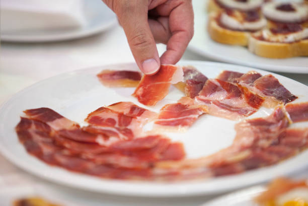 hand taking iberian cured ham slice from plate - serrano chilli pepper meat ham spain imagens e fotografias de stock