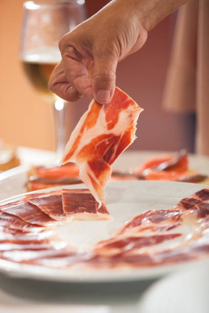 hand taking iberian cured ham slice from plate - serrano chilli pepper meat ham spain imagens e fotografias de stock