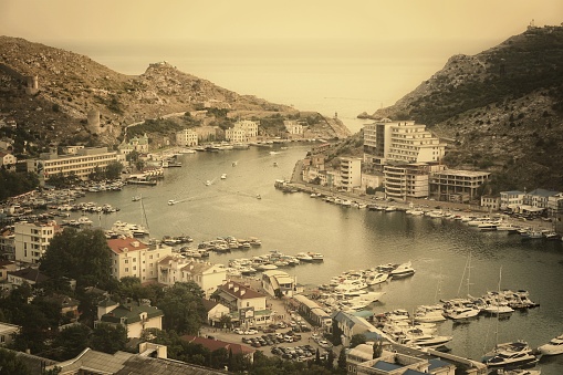 Panoramic view to Balaklava, Sevastopol, Crimea, Russia. View from high top to balaklavskaya bay with many little ships, boats. Black sea with mountains and comfort bay for sail boat stands.