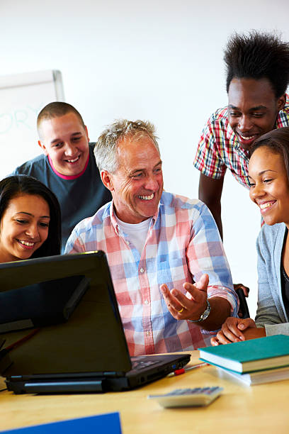 istock happy teacher showing students something on laptop 106520970