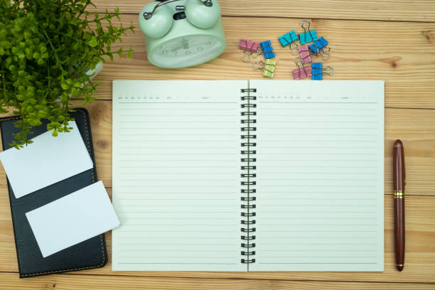 istock Office supplies or office work essential tools items on wooden desk in workplace, pen with notebook and alarm clock, top view 1065217956