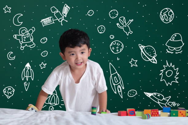 istock Asian kid learning by playing with his imagination about science and space adventure, hand drawn on the green chalkboard, education back to school and discovery concept. 1065218072