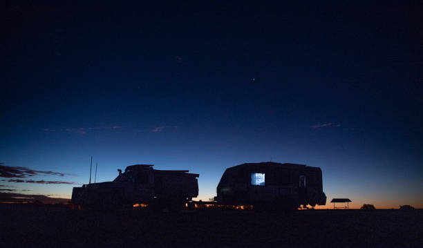 Outback Caravan Seen is a 4wd and caravan with the sun setting behind it near the outback town of Birdsville, Queensland Australia. ian stock pictures, royalty-free photos & images