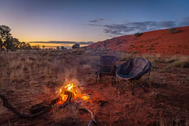 Seen is a campfire and chairs at sunrise