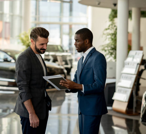 sprzedawca rozmawia z szczęśliwym mężczyzną w salonie samochodowym - car african descent shopping car dealership zdjęcia i obrazy z banku zdjęć