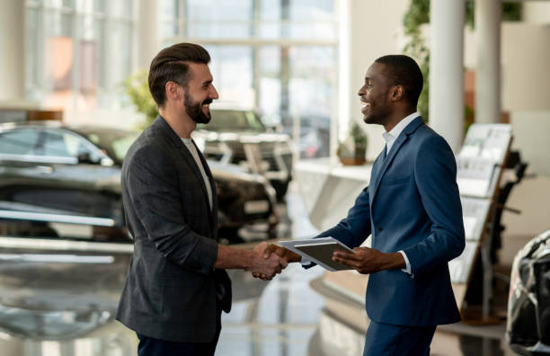 Customer closing a deal with a salesman at a car dealership Portrait of a customer closing a deal with a salesman at a car dealership and looking very happy handshaking car dealership stock pictures, royalty-free photos & images