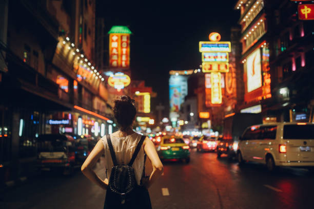 Tourist woman in Bangkok at night Young tourist woman enjoying walking on the streets of Bangkok in the evening, through the famous streets of Bangkok's Chinatown. bangkok street stock pictures, royalty-free photos & images