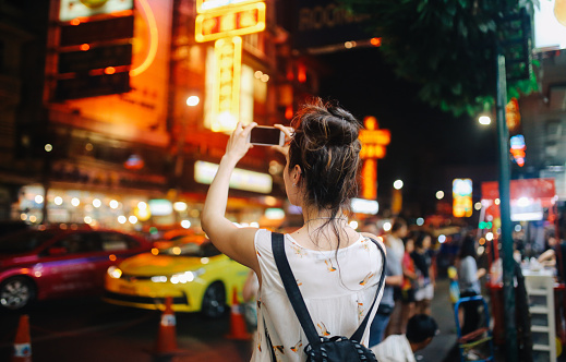 Young tourist woman enjoying walking on the streets of Bangkok in the evening, through the famous streets of Bangkok's Chinatown.