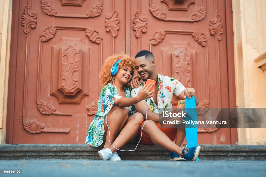 Couple sitting listening to music Couple - Relationship, Music, Headphones, Street, Afro Music Stock Photo