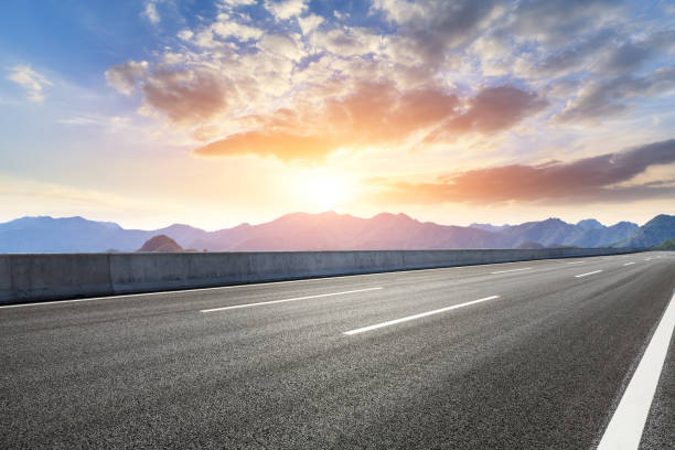 istock Asphalt road and mountains at beautiful sunset 1065252388