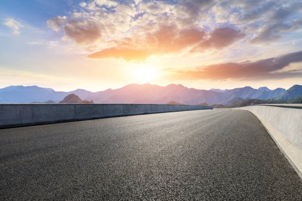istock Asphalt road and mountains at beautiful sunset 1065252646