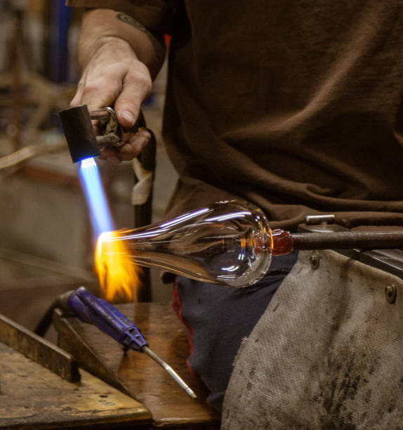 A glass blowing artist forms a blob of glass into a vessel using a gas torch A glass blowing artist forms a blob of glass into a vessel using a gas torch in Vermont hand blown glass stock pictures, royalty-free photos & images