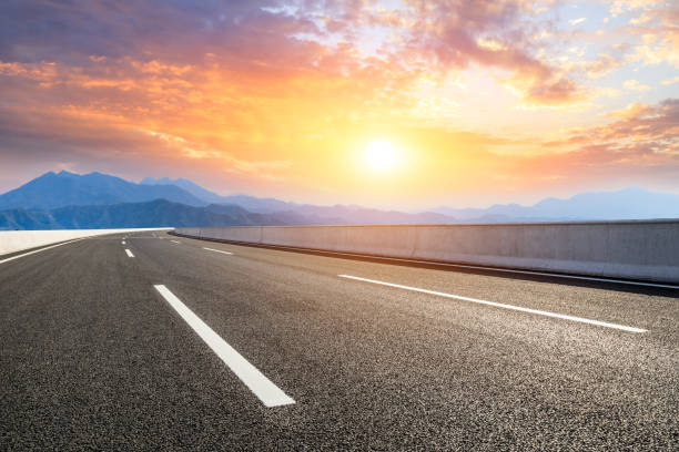 istock Asphalt road and mountains at beautiful sunset 1065256920