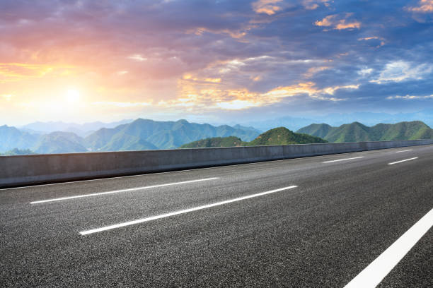 istock Asphalt road and mountains at beautiful sunset 1065259802
