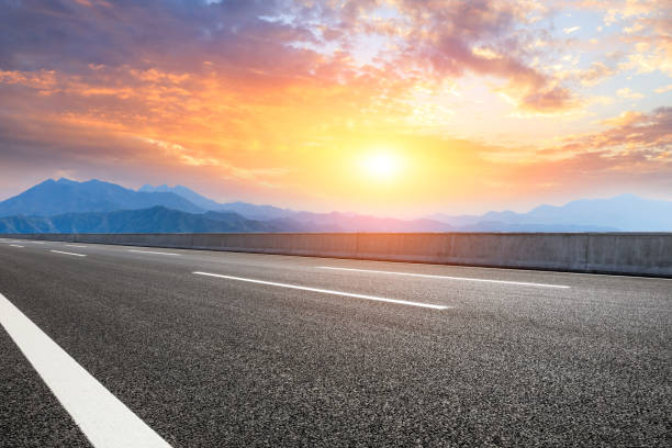 istock Asphalt road and mountains at beautiful sunset 1065259892