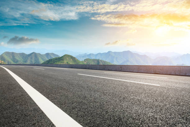 istock Asphalt road and mountains at beautiful sunset 1065261246