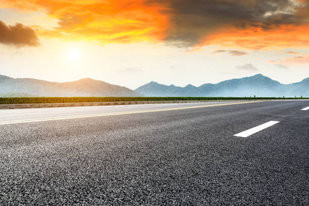 istock Asphalt road and mountains at beautiful sunset 1065261760